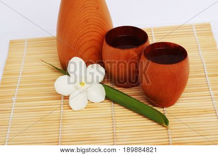 SAKE liqueur in a brown wooden bottle on a light brown background.