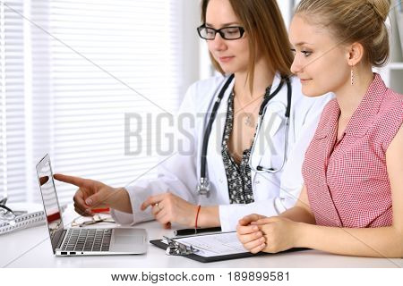 Doctor discussing confidental medical history with his patient and pointing at monitor computer.