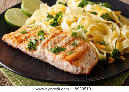 Grilled Salmon Garnished With Fettuccini Pasta With Cheese, Herbs Closeup. Horizontal