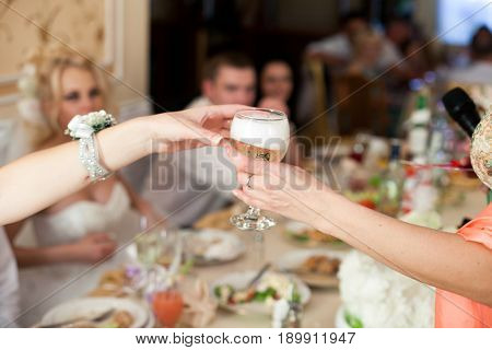 Woman gives a glass with champagne to someone over the table