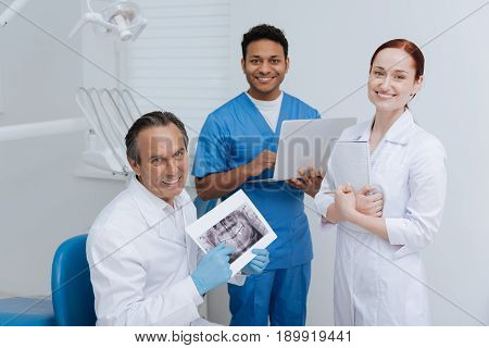 New students. Two interns standing around their mentor and holding their gadgets while looking straight at camera