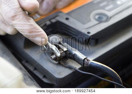 Car workshop. Car service. The mechanic unscrews the battery clutch from the battery in the car