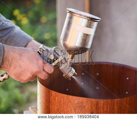 Carpenter spraying lacquer on wooden drum shell closeup