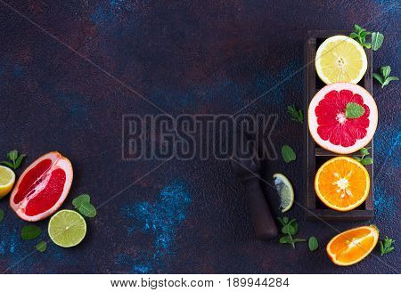 Orange, lemon and grapefruit with citrus reamer, copy space on dark background