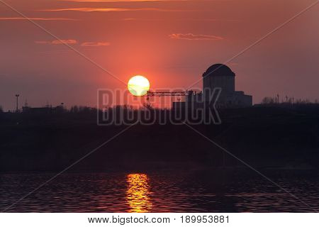 Crimson sunset at Voronezh water reservoir. Silhouette of nuclear power plant.