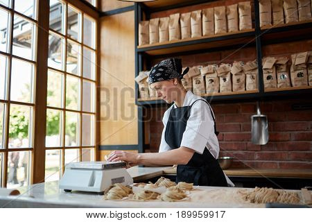 Horizontal indoors shot of female cook forming taglatellepasta in a kitchen of restaurant. Woman forming taglatellein cafe