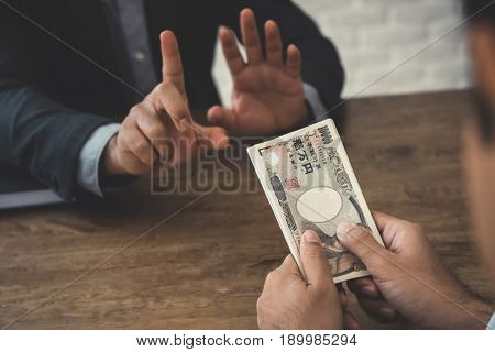 Businessman refusing money Japanese yen bills - anti bribery and corruption concepts