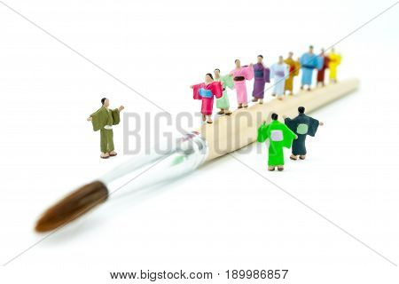 Miniature Japanese peoples wearing kimono walking on paintbrush