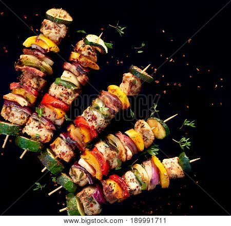Grilled meat and vegetable skewers with fresh herbs and spices, top view