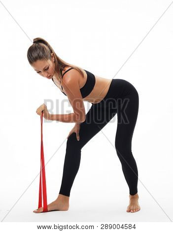 Motivation, fitness and people concept: Sporty woman  doing a exersize  with resistance band. Photo of young woman in fashionable sportswear on white background.  