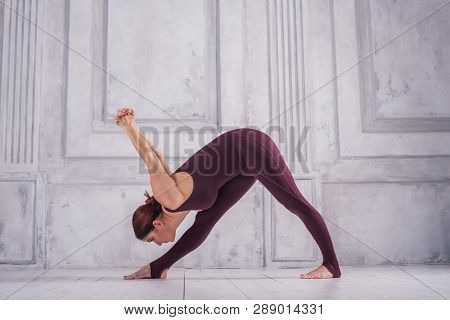 Woman Meditating In A Gym. Sporty Young Woman Doing Yoga Practice On Light Background.  Pyramid Or O
