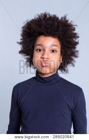 African American Dark-haired Kid Inflating Cheeks While Wearing Blue Turtleneck