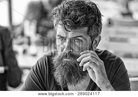 Man With Beard And Mustache Sits Outdoor At Cafe Terrace. Bearded Man On Calm Face Looks Sad And Tro