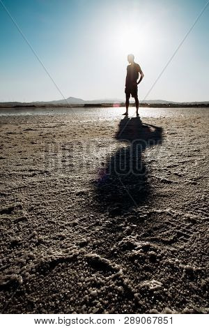 Single Man Walking On Dry Salt Lake In Limassol, Cyprus. Alone And Walking In Desert Conditions.