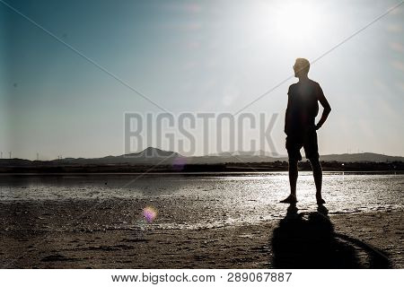 Single Man Walking On Dry Salt Lake In Limassol, Cyprus. Alone And Walking In Desert Conditions.