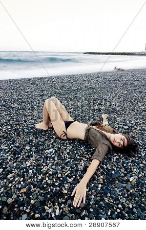 美しい女性の悲しいジェスチャーで浜辺を敷設します。長い露出の波。