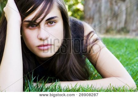 芝生の上を敷設若い見つめる女性