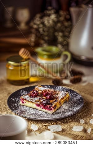 Clafoutis Cherry Pie On A Dark Plate. Klafuti French Cherry Pie With Honey.