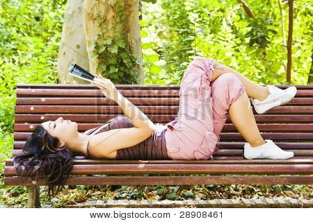 美しい女性の公園のベンチで読書。