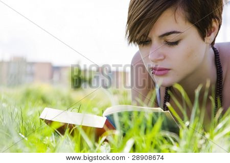 草の上を読んで若い美しいブロンド
