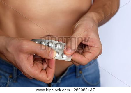 Man Taking Pills, Blister Pack With Tablets In Male Hands Close Up. Muscular Guy In Unzipped Jeans W