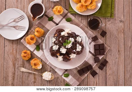 Chocolate Profiteroles With Whipped Cream On White Dish.