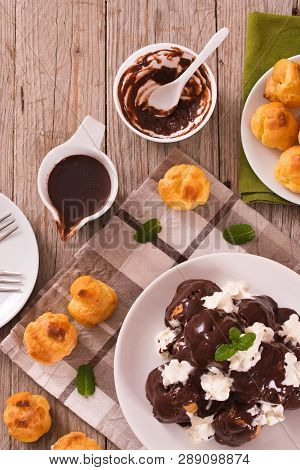 Chocolate Profiteroles With Whipped Cream On White Dish.