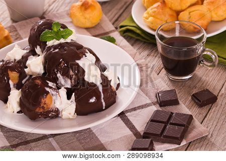 Chocolate Profiteroles With Whipped Cream On White Dish.