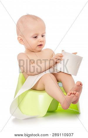 Baby Learning How To Use Chamber Pot. Sitting On The Potty With Toilet Paper Rolls Isolated On White