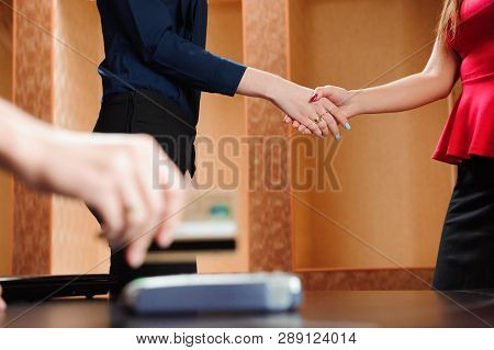 Hand Swiping Debit Card On Pos Terminal. Business People In Office Holding A Conference And Discussi