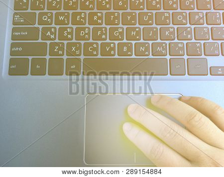 Human Hand Touching On Laptop Trackpad For Cursor Movement With Soft Light Focus On Finger.
