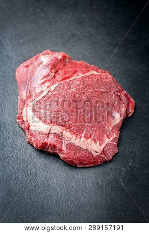 Traditional German raw beef cheeks as closeup on a black board 
