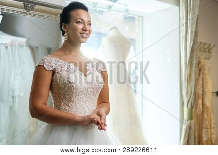 Beautiful bride choosing wedding dress in a wedding salon