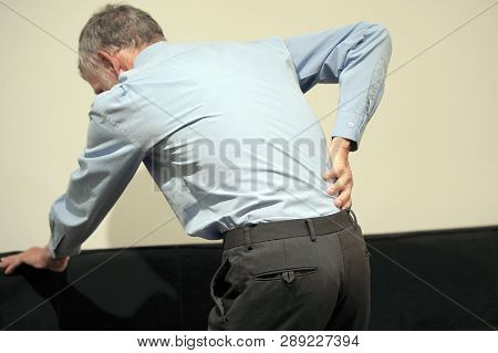 Elderly Man With Pain In Kidneys. Old Man With Back Ache Clasping Her Hand To Her Lower Back. Man Su