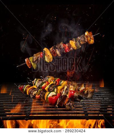 Tasty skewers on iron cast grate with fire flames.