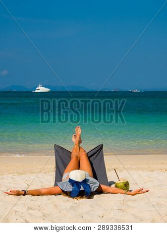Woman with straw hat enjoying her holidays on a transat at the tropical beach in Thailand