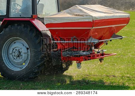 Unrecognizable Farmer In Agricultural Tractor Is Fertilizing Wheat Crop Field With Npk Fertilizer Nu
