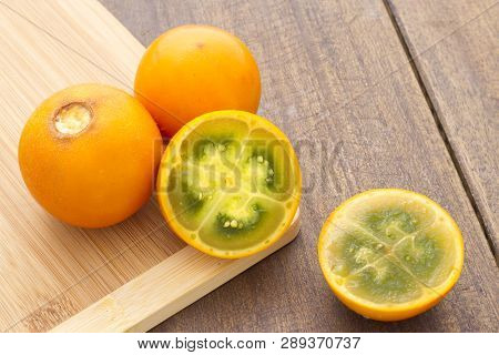 Fruits And Slices Of Lulo Or Naranjilla On The Wooden Table - Solanum Quitoense