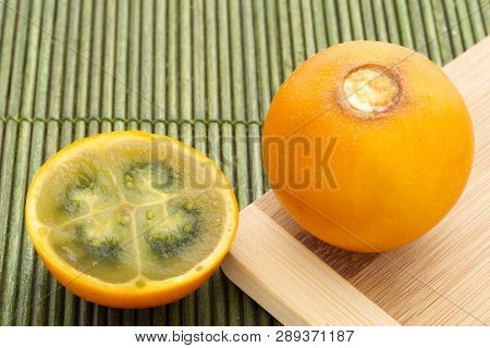 Fruits And Slices Of Lulo Or Naranjilla On The Wooden Table - Solanum Quitoense