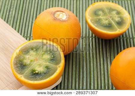 Fruits And Slices Of Lulo Or Naranjilla On The Wooden Table - Solanum Quitoense