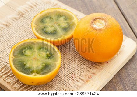 Fruits And Slices Of Lulo Or Naranjilla On The Wooden Table - Solanum Quitoense