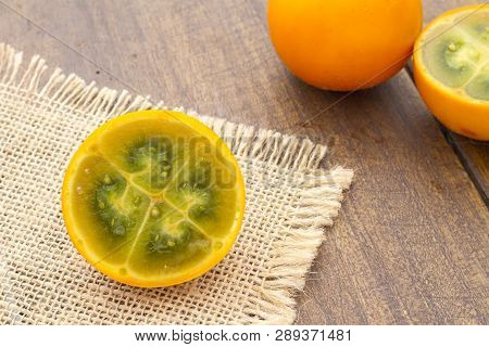 Fruits And Slices Of Lulo Or Naranjilla On The Wooden Table - Solanum Quitoense