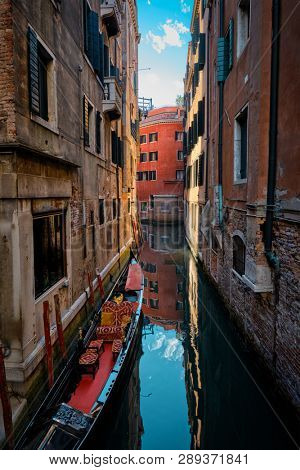 Narrow canal between colorful old houses with gondola boat in Venice, Italy