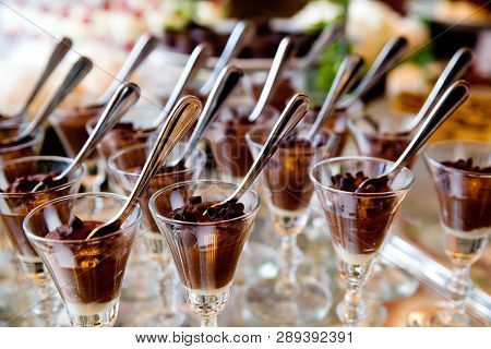 details from a wedding dessert table - chocolate mousse in fancy glasses with spoons