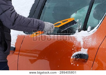 Car Covered With Snow. Man Brushing And Shoveling Snow Off Car After Snow Storm. Brush In Mans Hand.