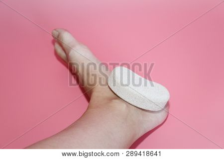 Pumice Stone For Foot Care. In The Photo A Woman Hand Holds A Pumice Near The Heel Of Her Foot. Remo