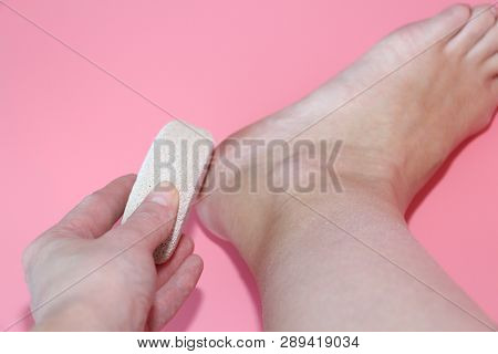 Pumice Stone For Foot Care. In The Photo A Woman Hand Holds A Pumice Near The Heel Of Her Foot. Remo
