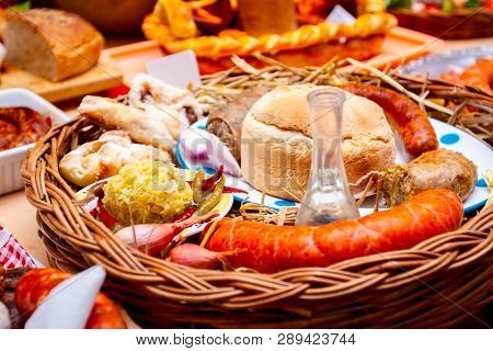 Decorated Sausages With Fresh Vegetables, Bread And Bottle Of Brandy Are Exposed On Traditional Saus