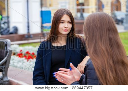 Two happy young women walking in autumn park, outdoors