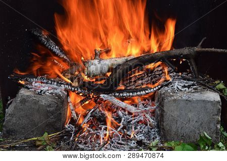 Bright Bonfire Under Two Stones At Garden For Cooking At Camp